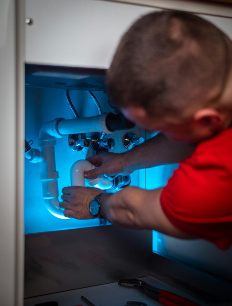 Plumber repairing pipework under a bathroom sink