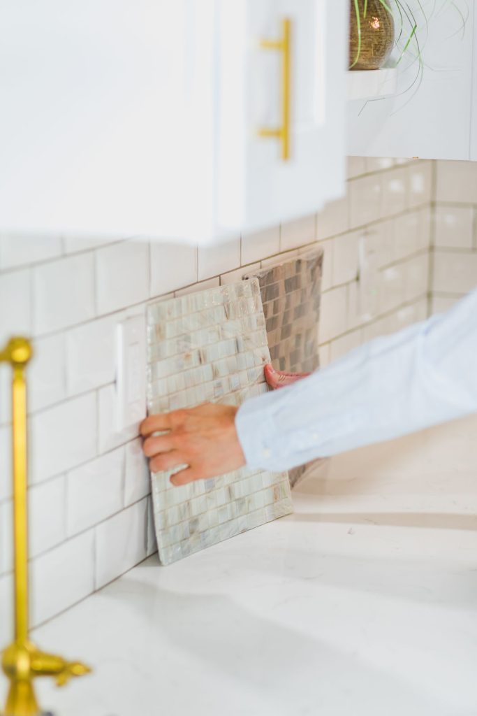 Holding a tile sample against a wall to choose a finish