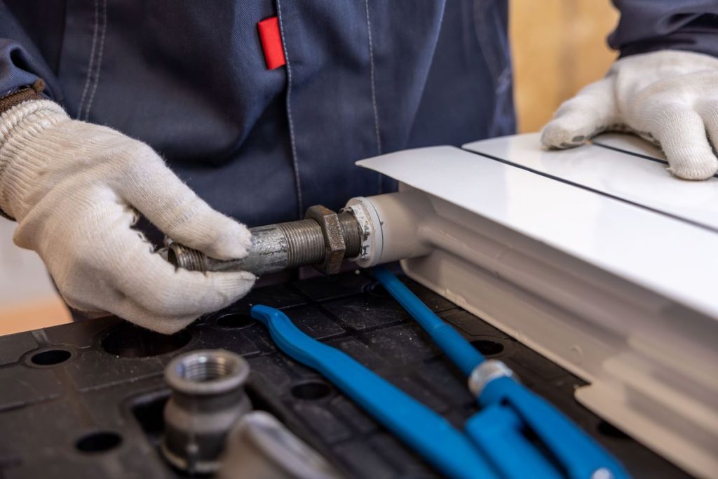 Plumber in gloves tightening a pipe fitting