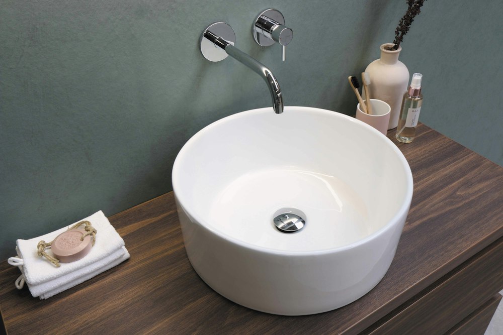 Round white ceramic basin with wall-mounted tap