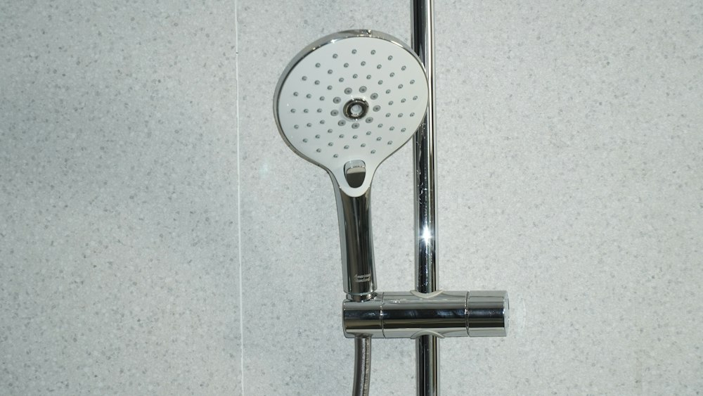 Chrome shower head and riser rail on white tiles