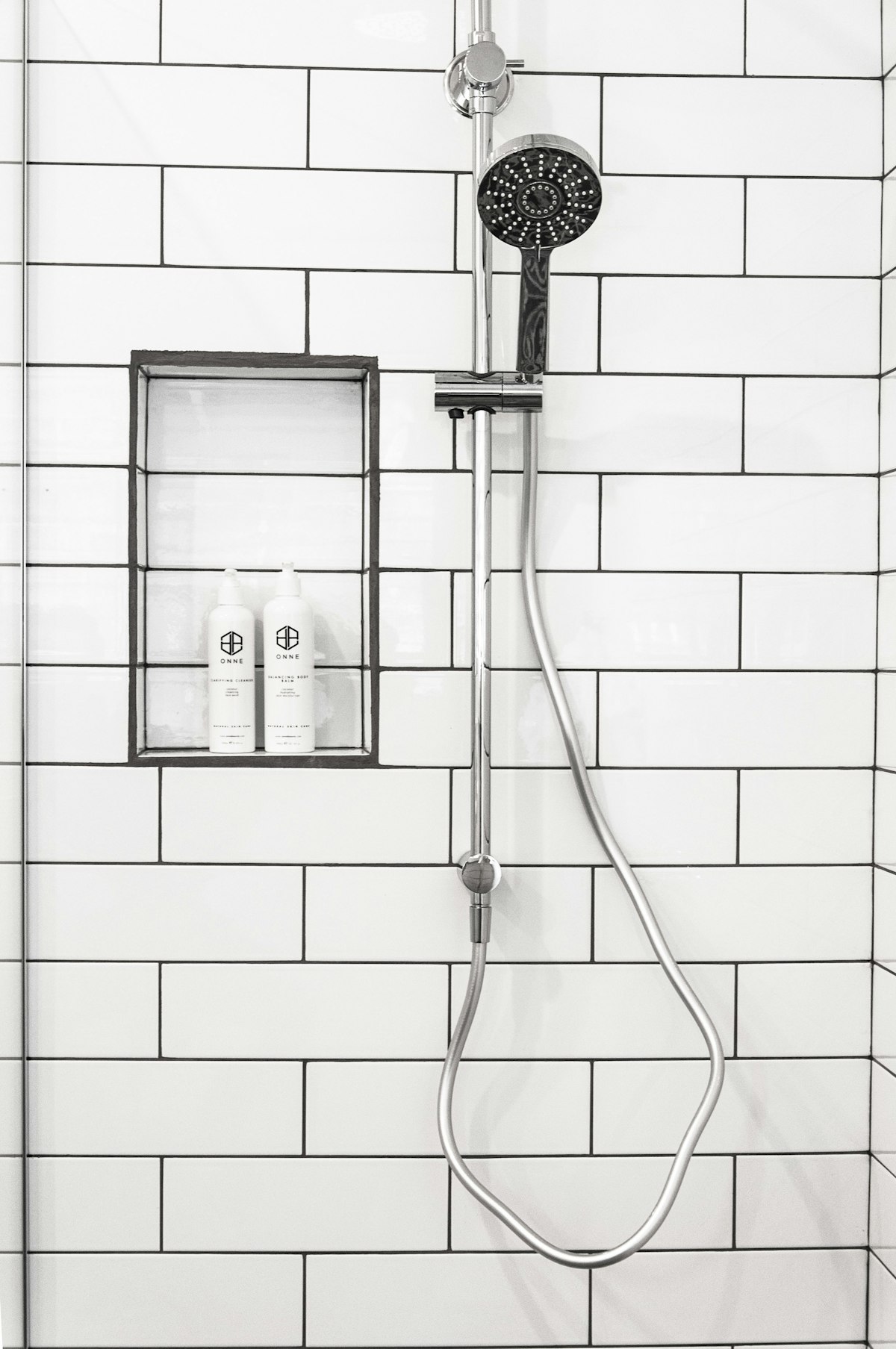Stainless steel shower head on white tiles