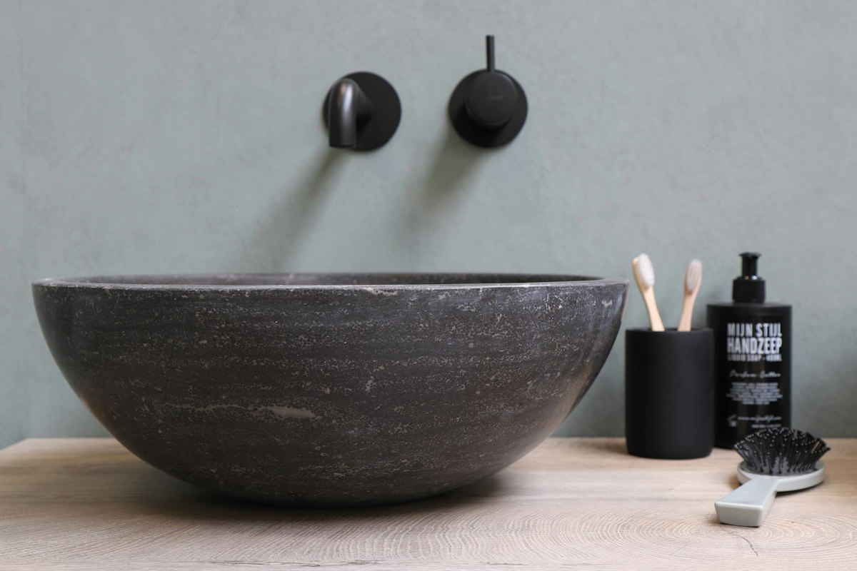 Stone vessel basin with matt black wall-mounted taps