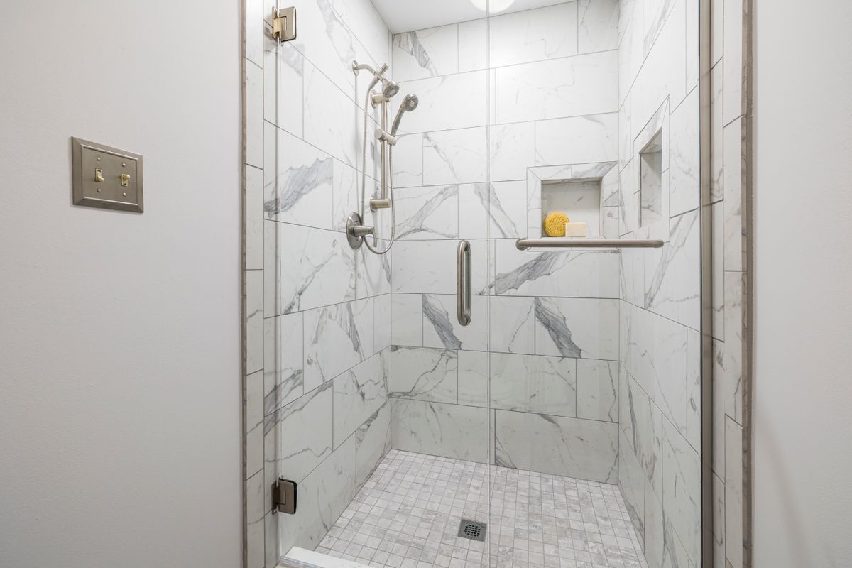 Tiled walk-in shower with glass door and recessed niche