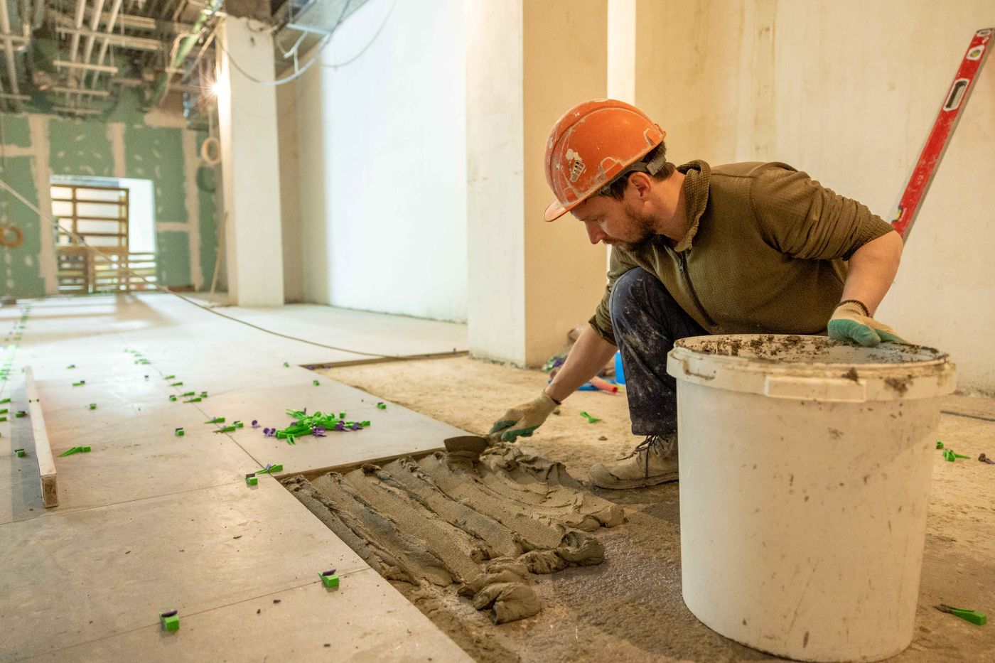 Tradesman laying floor tiles during a bathroom renovation