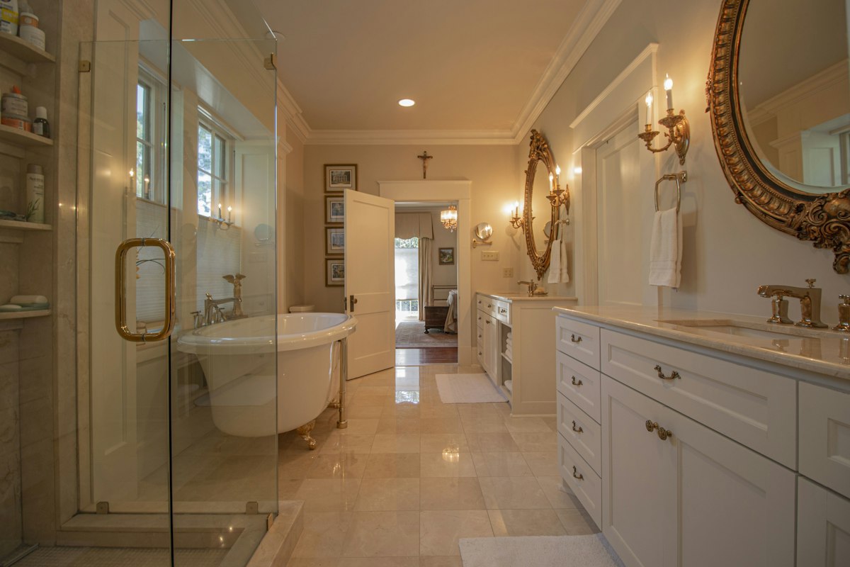 Warm-lit bathroom with glass shower stall and cabinetry
